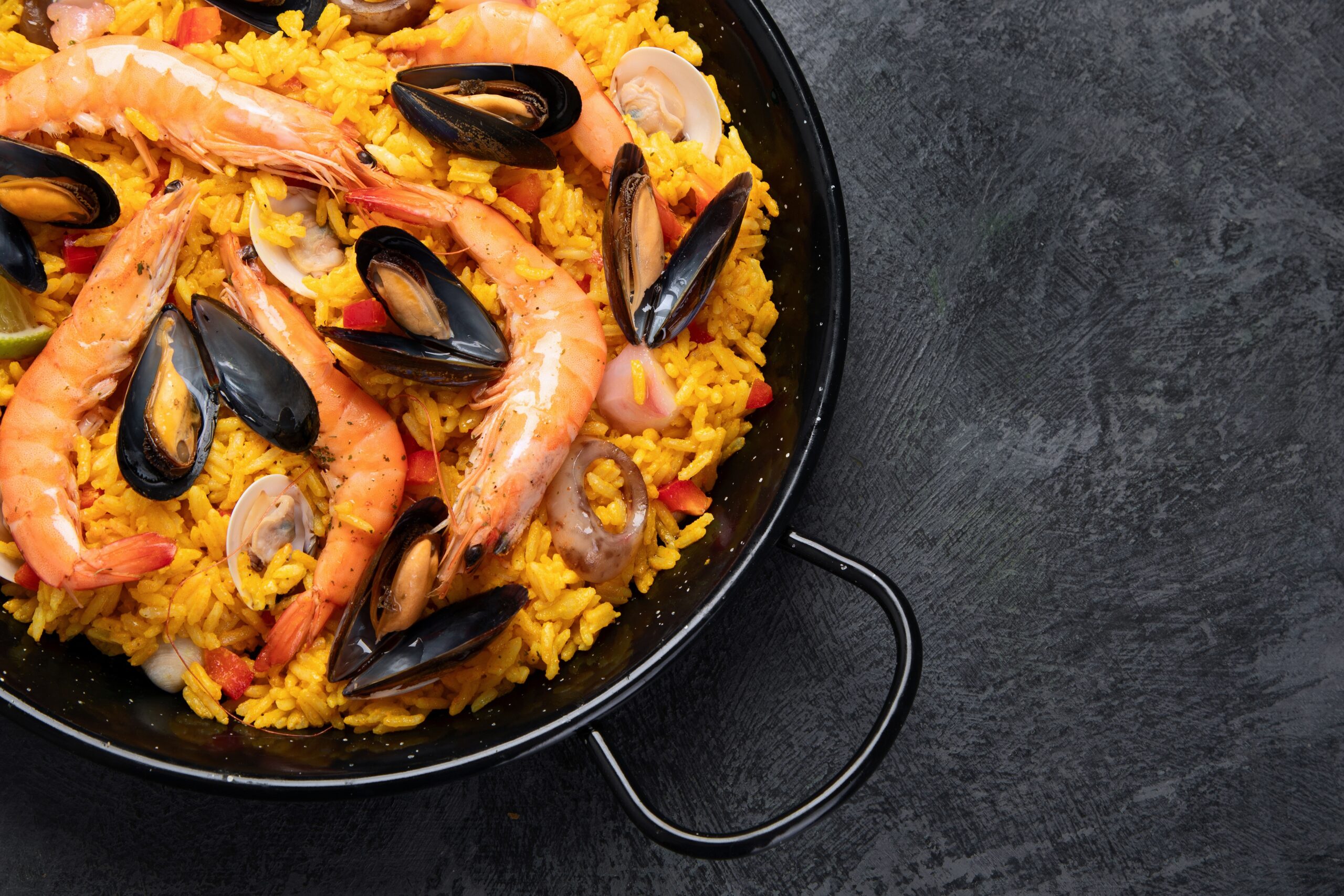 Spanish paella with rice, seafood, and vegetables in a wide pan