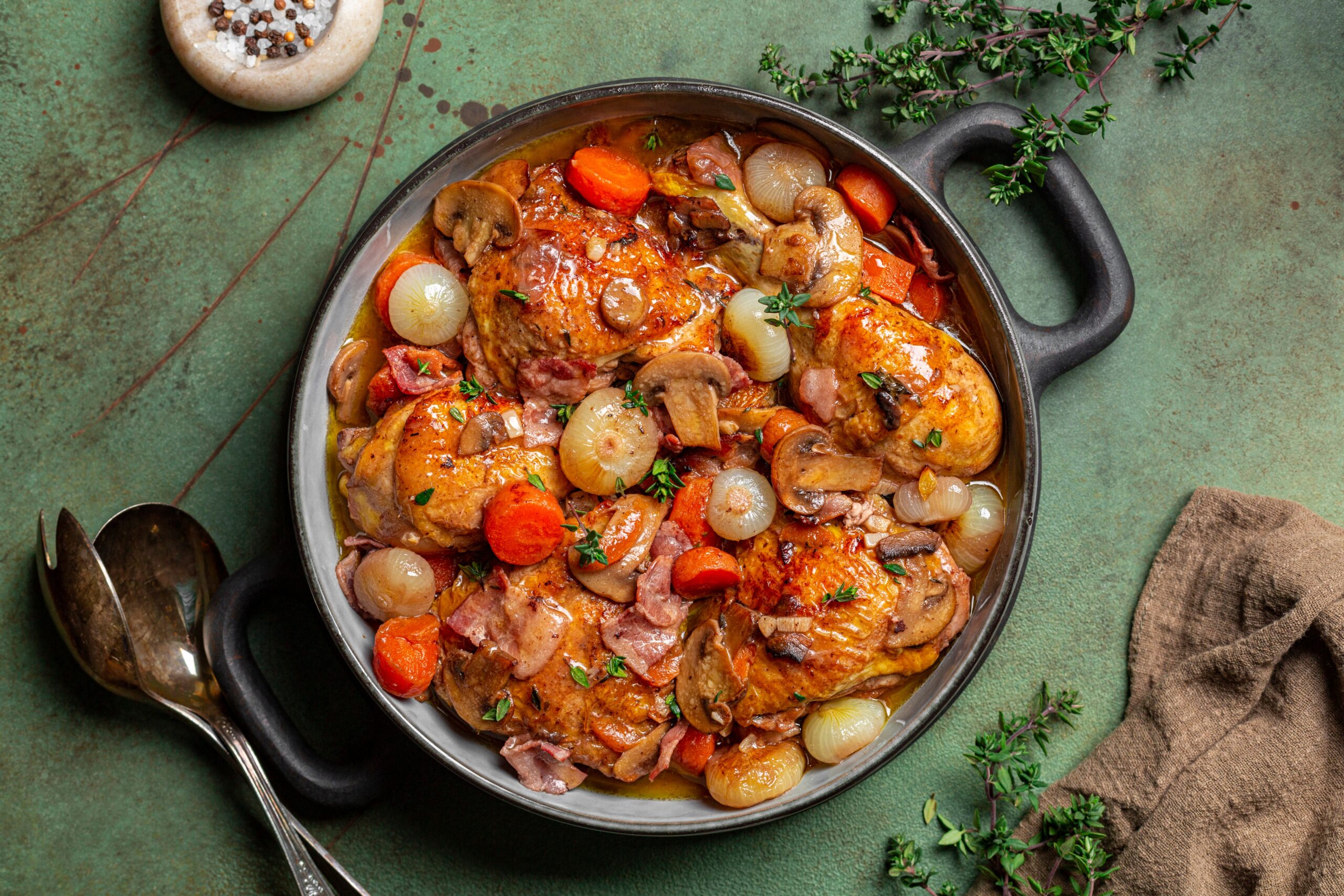 Coq au vin with chicken, wine, mushrooms, onions, and bacon in a pot