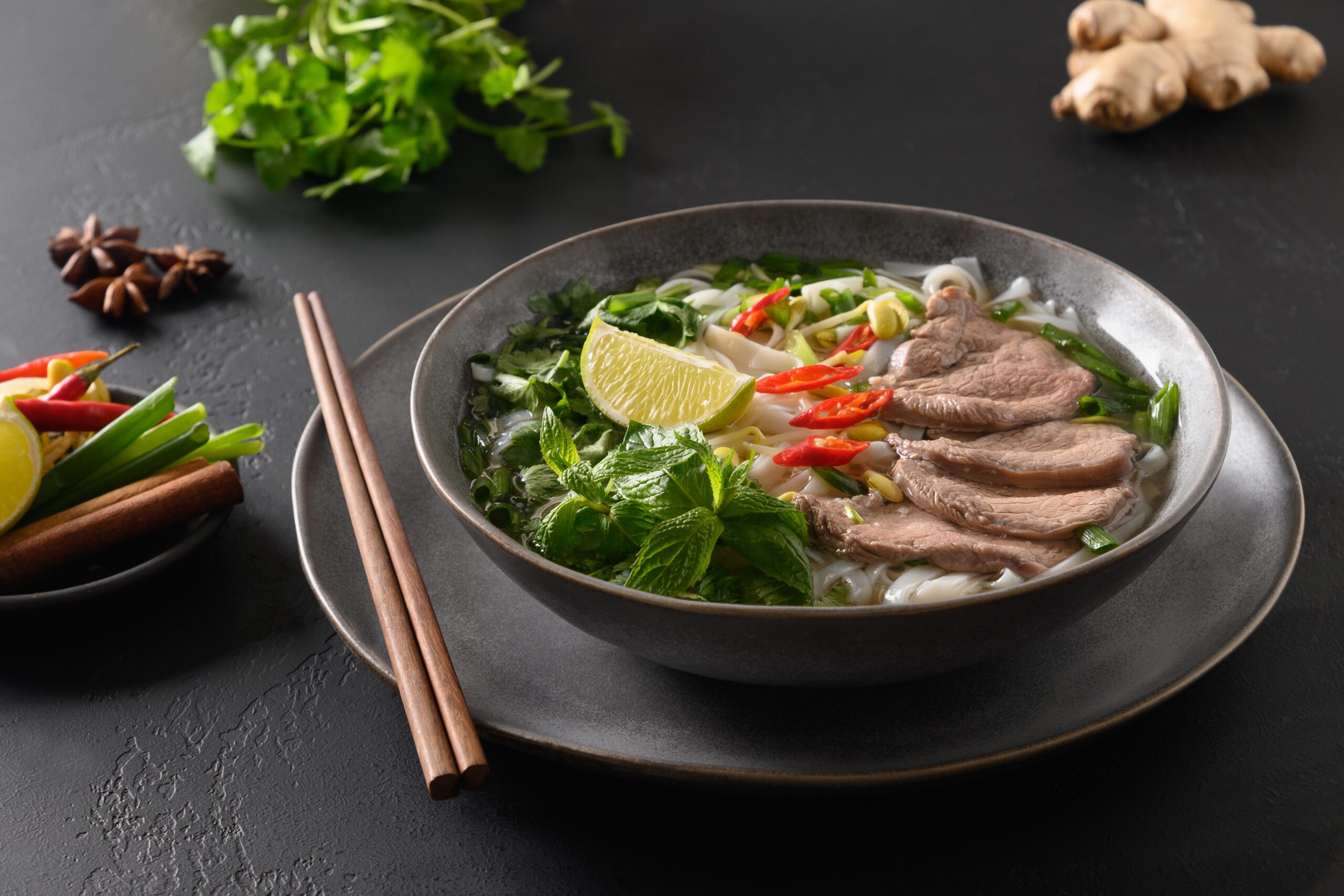 Vietnamese pho with rice noodles, broth, and fresh herbs in a bowl